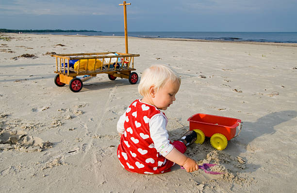 Young girl with beautiful long hair digging a hole in the sand at sunlit beach. Perfect for family/holiday/relaxation purposes.