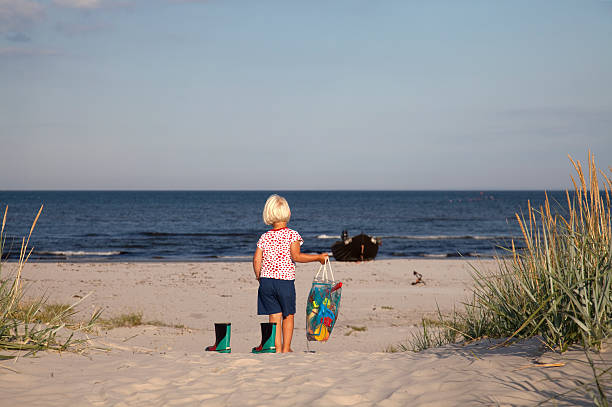 Little girl playing with dirt on a beach.