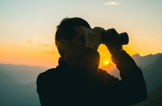 istock Man looks through binoculars in mountain 1064164428