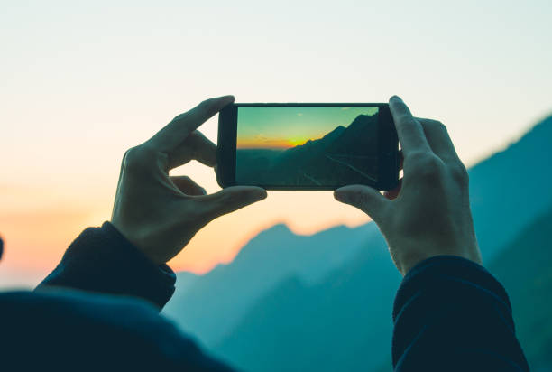 Man photographing mountain with mobile phone