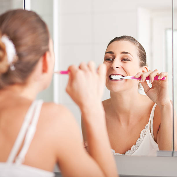 istock Young woman brushing teeth in front of mirror 106416767