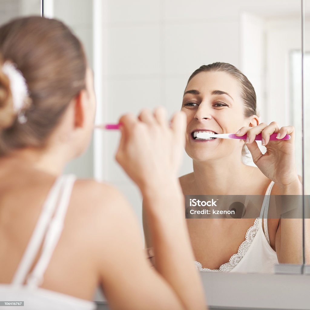 Молодая женщина, Чистить зубы перед зеркалом - Стоковые фото Впереди роялти-фри