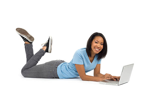souriant adolescents sur un ordinateur portable - être étendu sur le ventre photos et images de collection
