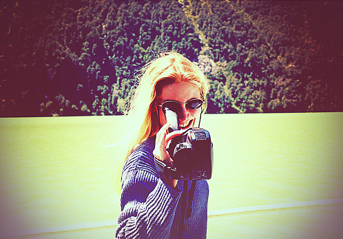 Vintage image of a young woman with old video camera looking at camera.