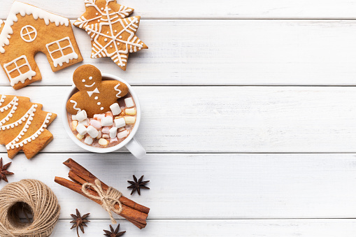 Sweet Christmas composition. Gingerbread cookie man in cup of hot chocolate on white background with copy space, top view