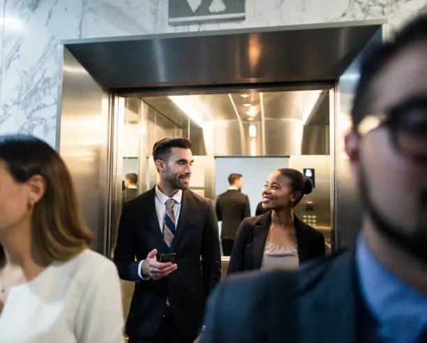 Photo of Young multi-ethnic business executives walking out of elevator