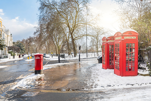 Red phone boxes in London with snow. Unusual view of the capital city covered by snow on a sunny and cold winter day. Travel and weather concepts