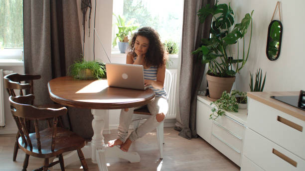 Charming young woman typing on laptop computer at home. stock photo