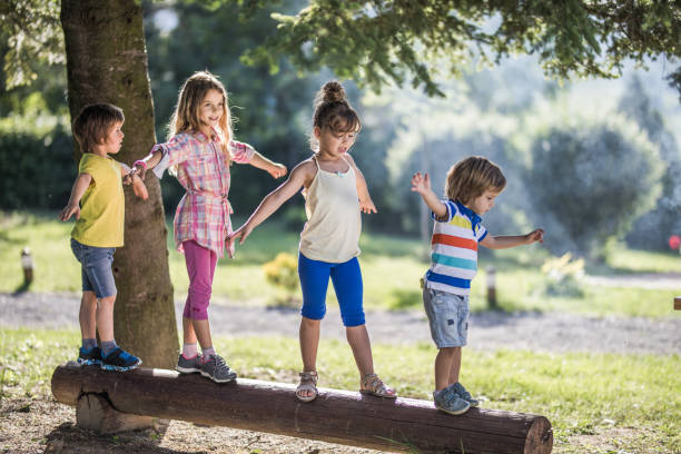istock Group of small kids walking on a tree trunk in nature. 1064179032