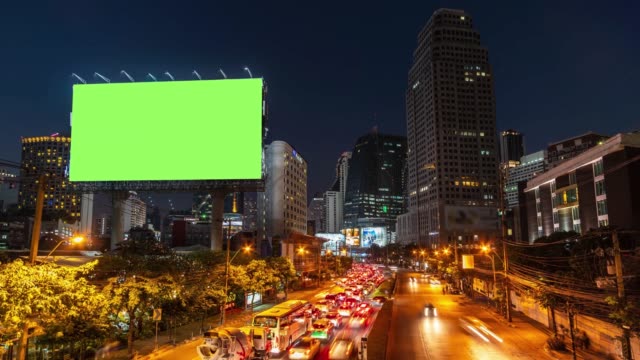 Time lapse: Billboard with green screen and city traffic light background at night. 4K Resolution.