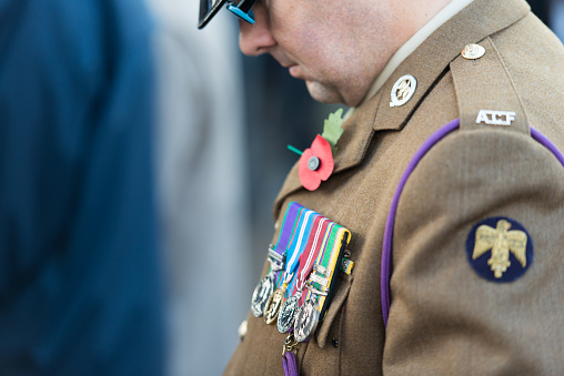 Picture of a the uniform of a serviceman from the Canadian Army, ground forces, standing during the Remembrance day, with details of a Remembrance poppy and medals, military decorations, commemorating the end of World War I on the 11th of November