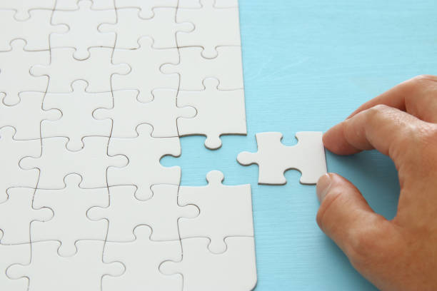 istock male hand putting the last piece in the puzzle. 1064199614