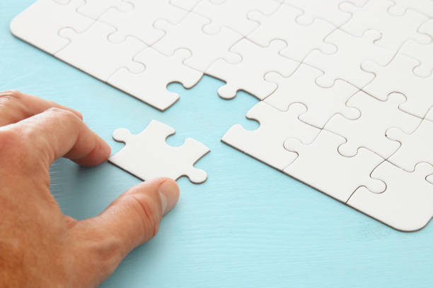 istock male hand putting the last piece in the puzzle. 1064199622