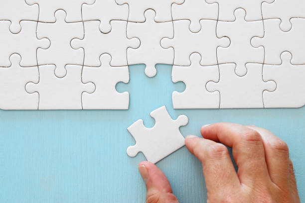 istock male hand putting the last piece in the puzzle. 1064199630