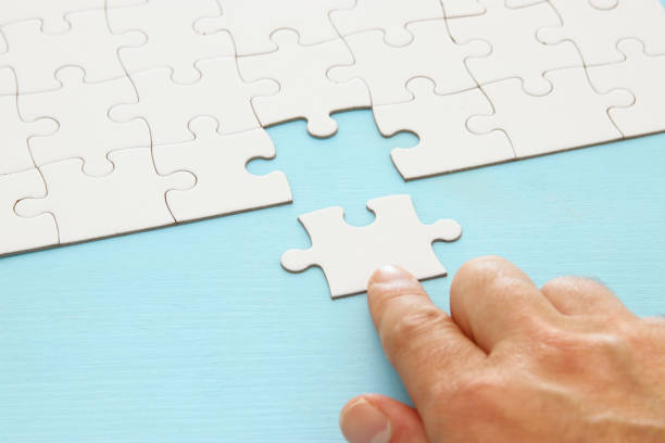 istock male hand putting the last piece in the puzzle. 1064199634