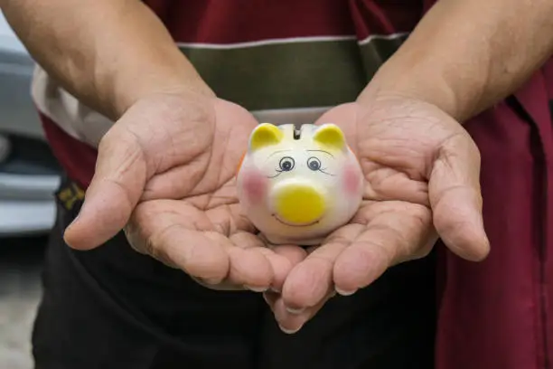 Photo of Closeup Asian Man hand holding a small Piggy Bank.
