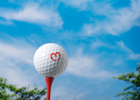There is a golf ball written the heart mark on tee