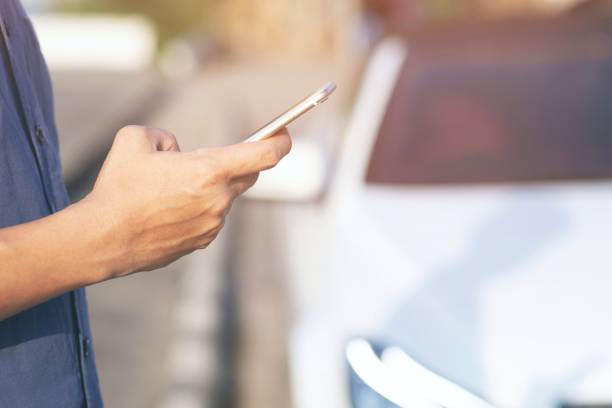 istock close up people man hand using a mobile smart phone call a car mechanic ask for help assistance because car broke roadside. standing wait beside broken car background. soft focus. 1064204770