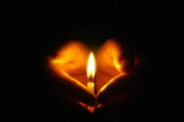 Photo of The hand that protects the candles in the dark.