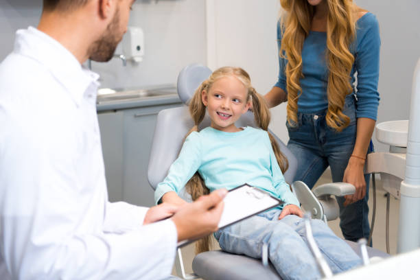 istock dentist with clipboard talking with little child while mother standing near her for support 1064214496