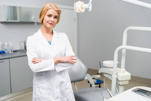 istock attractive young dentist with crossed arms looking at camera in office 1064214704