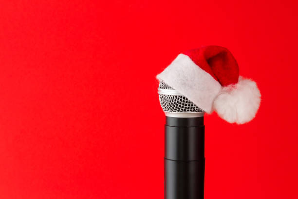 microfone no chapéu de papai noel em um fundo vermelho, acessórios festivos de natal - santa claus audio - fotografias e filmes do acervo