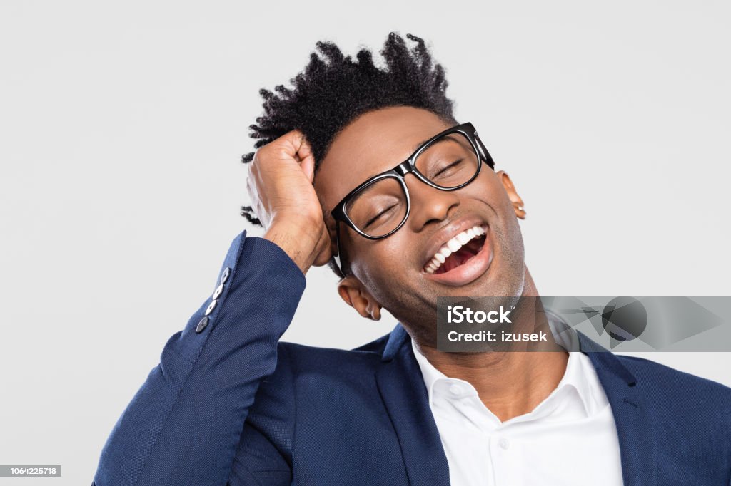 Afro american businessman laughing Happy young businessman smiling with hand in head on gray background. Afro american businessman laughing with eyes closed. Cut Out Stock Photo