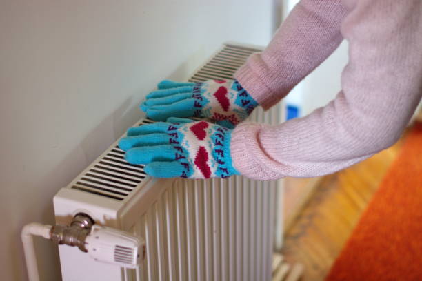 istock Hands in wool gloves on radiator 1064226712