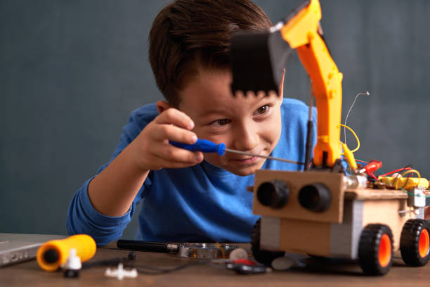 Elementary age school boy builds robot 6-7 years old cute boy builds robot for his school project genius at school stock pictures, royalty-free photos & images