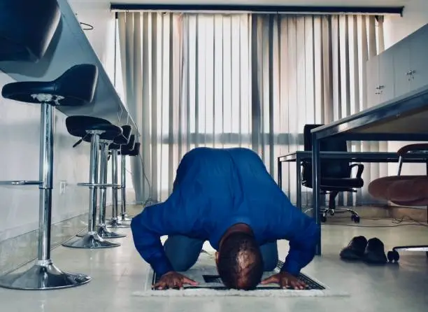 Photo of Muslim man praying in the corporate office head on the floor