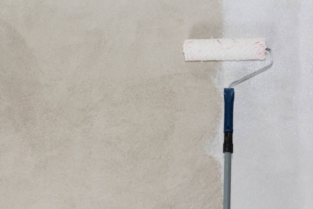 istock Close up of painter i'm painting a wall with paint roller. 1064255046