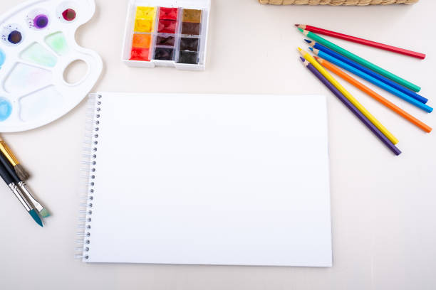 istock Painter artist work space paper pencil paintbrush paints from above bright white background 1064255084