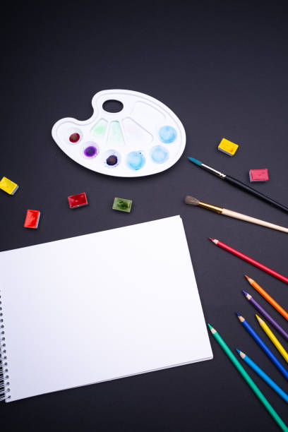 istock Painter artist work space paper pencil paintbrush paints from above dark background 1064255174