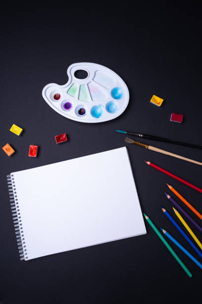 istock Painter artist work space paper pencil paintbrush paints from above dark background 1064255190