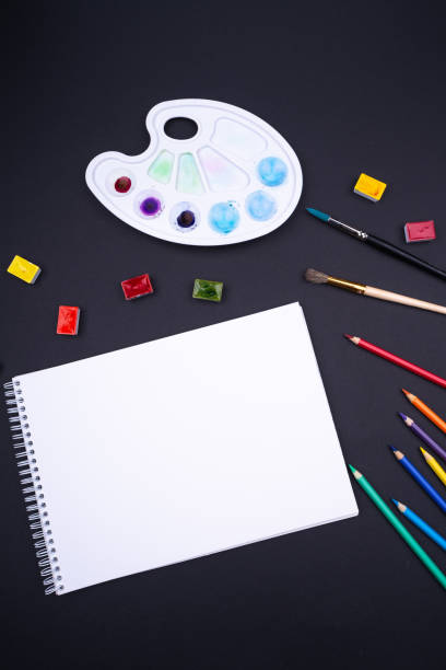 istock Painter artist work space paper pencil paintbrush paints from above dark background 1064255220