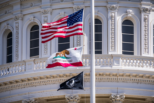 September 22, 2018 Sacaramento / CA / USA - The US flag, the California flag and the POW-MIA flag waving in the wind in front of the Capitol State Building in downtown Sacramento
