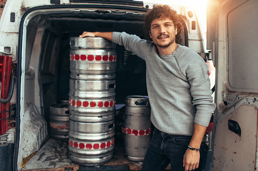 Young businessman standing by the kegs.