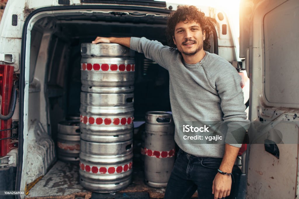 Craft Brewery Young businessman standing by the kegs. Brewery Stock Photo