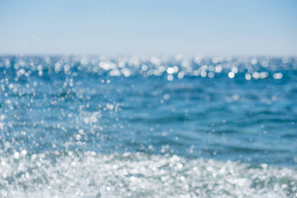 Abstract bokeh background from summer blue sea water at the beach Abstract bokeh background from summer blue sea water at the beach, panoramic view glittering sea stock pictures, royalty-free photos & images
