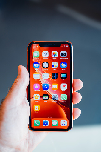 STRASBOURG, FRANCE - OCT 26, 2018: Customer POV holding new red iPhone XR smartphone admiring all home apps screen
