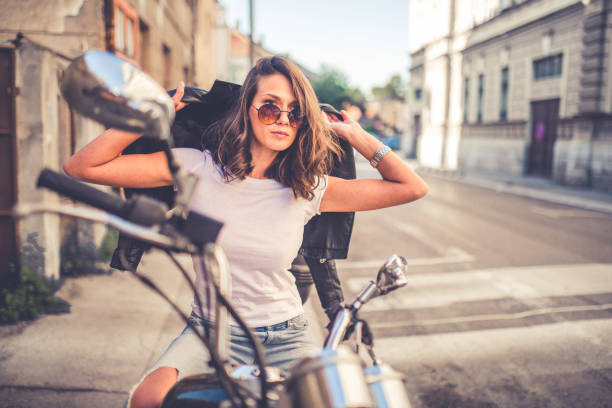 Young pretty fashioned girl sitting on her motorcycle