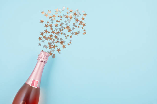 creative photo of champagne bottle with confetti on blue background - champagne pink luxury table imagens e fotografias de stock