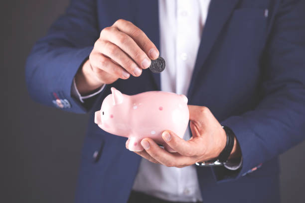 istock young man hand piggy bank with coin 1064288628