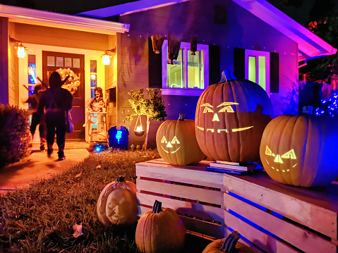 Kids Trick or treating on Halloween night in suburban Californian house decorated with jack o' lantern pumpkins. Photographed in San Jose, California with the p20pro mobile phone.