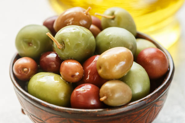 istock Mixed marinated olives (green, black and purple) in ceramic bowl  and olive oil 1064289310