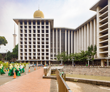 Jakarta national Istiqlal mosque side view with group of muslim women walking away from the building.
