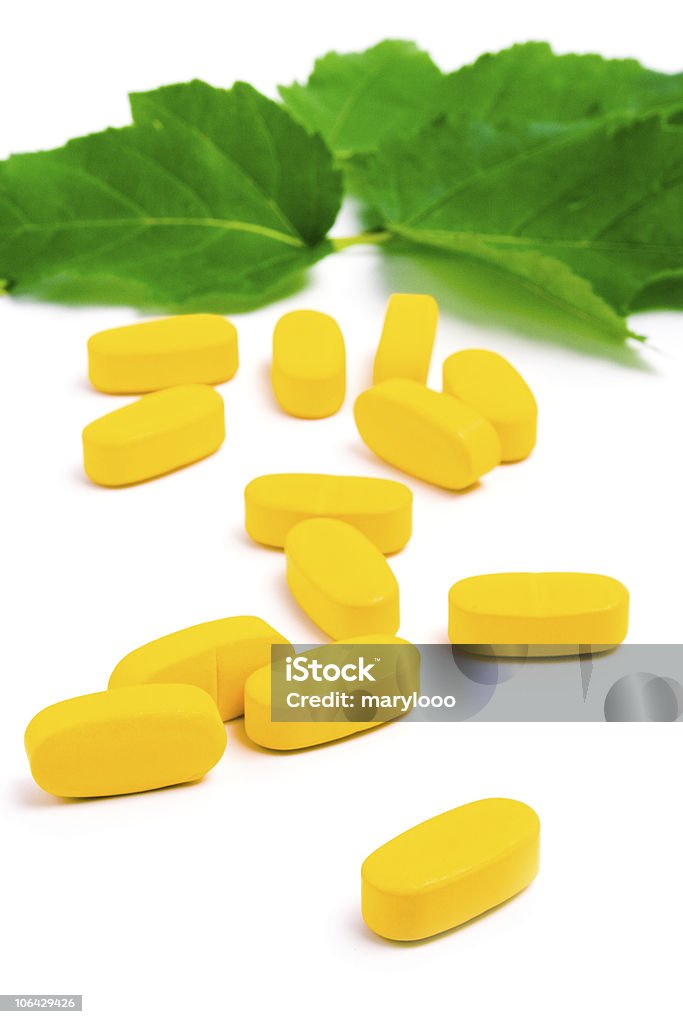 黄色のビタミン薬、緑の葉 - カットアウトのロイヤリティフリーストックフォト