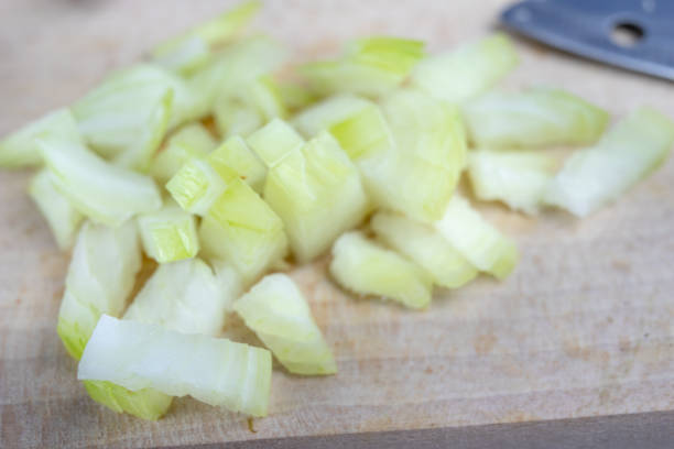 istock Onion on a chopping board on a white kitchen table. Vegetables for preparing dishes in the home kitchen. White background. 1064304418