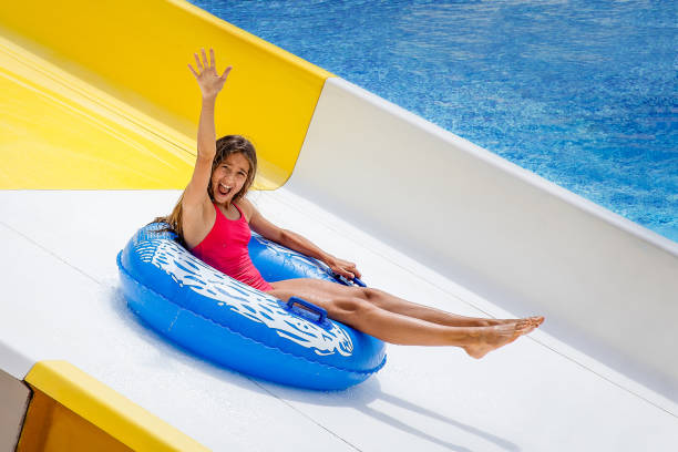 menina bonita no anel inflável, corrediça de água com a mão a subir no parque aquático - inflatable slide sliding child - fotografias e filmes do acervo