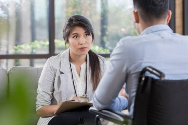 istock Therapist talks with man in wheelchair 1064312798